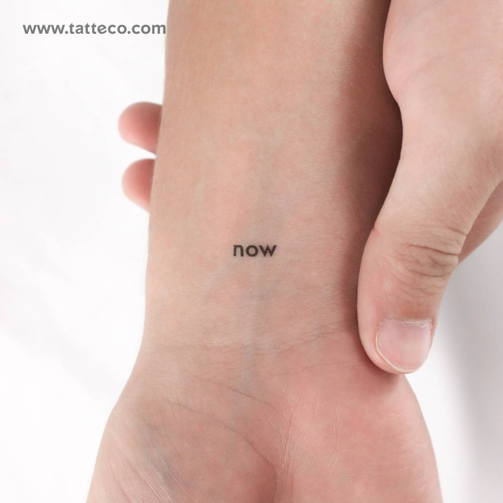 Tiny word "now" temporary lettering tattoo placed on the wrist.