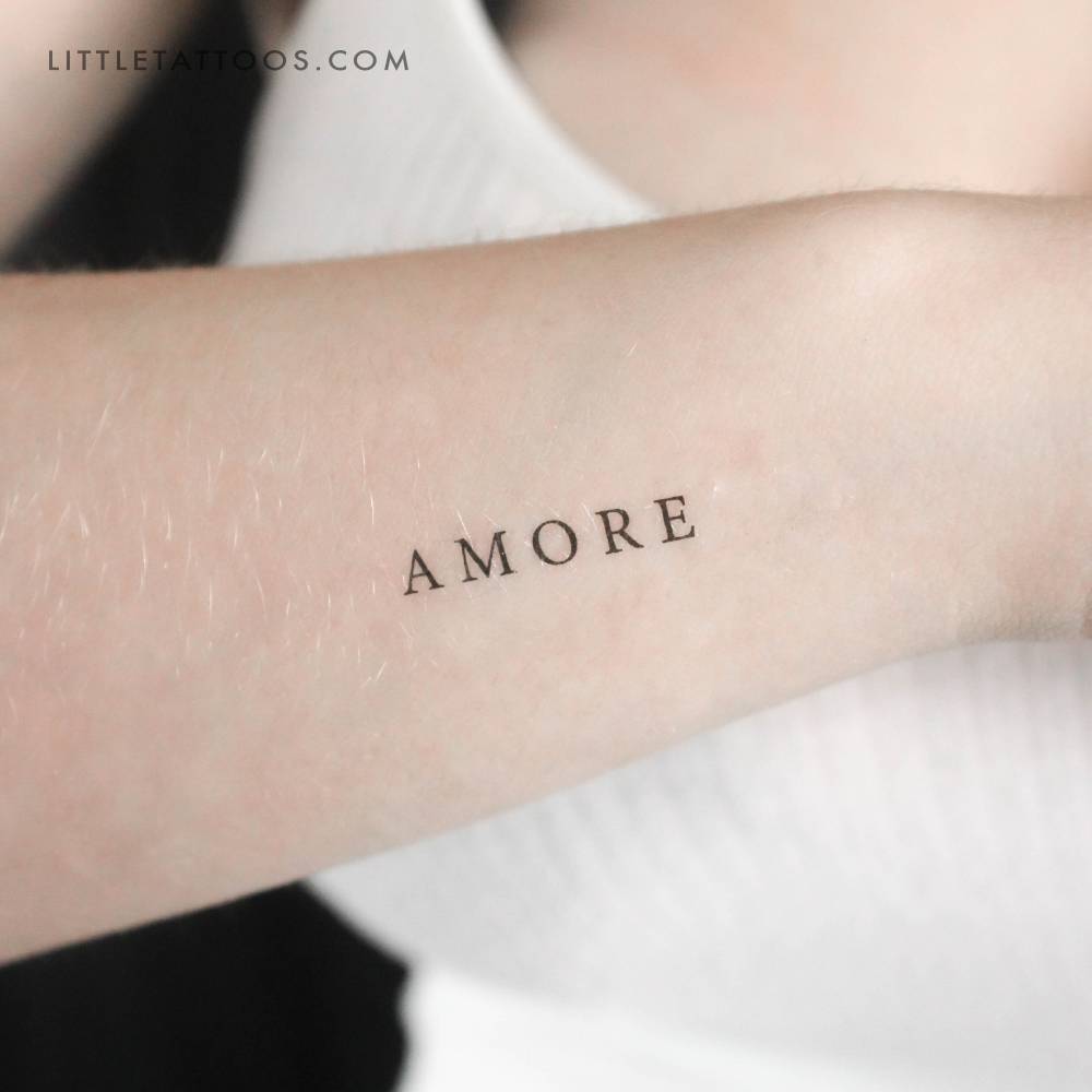 Capital "amore" temporary lettering tattoo located on the wrist.