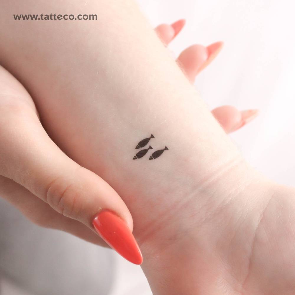 Minimalistic style three little fish temporary tattoo located on the wrist.