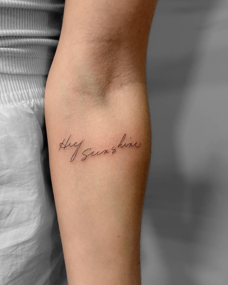 "Hey sunshine" lettering tattoo located on the inner forearm.