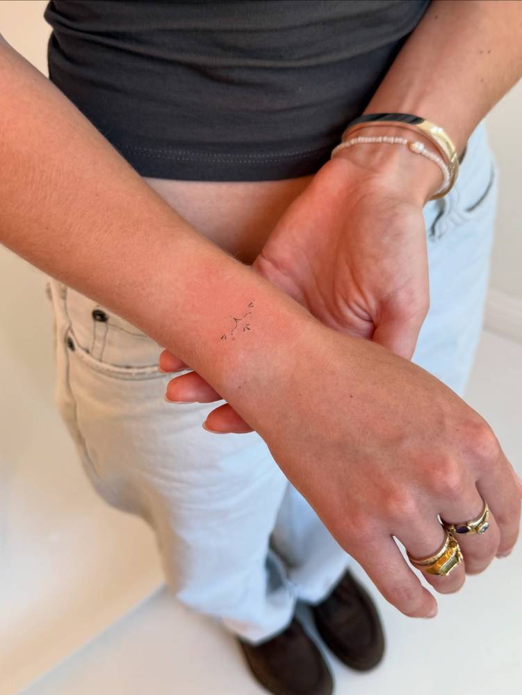 Tiny minimalistic ornamental tattoo placed on the wrist.