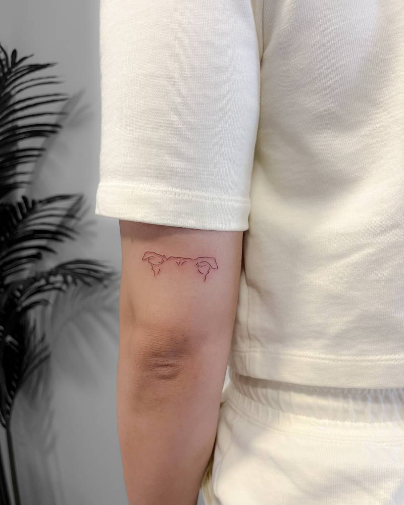 Little dog ears tattoo in fine line style done on the tricep.