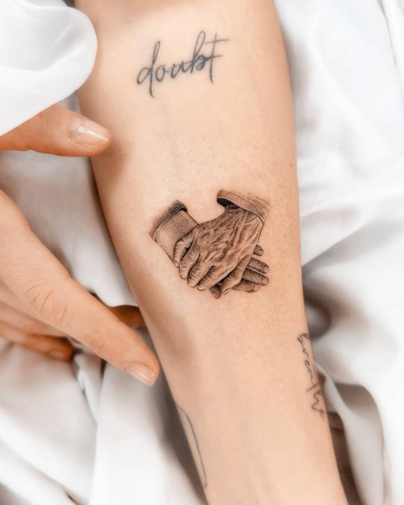 Holding hands tattoo in micro-realistic style located on the inner forearm.