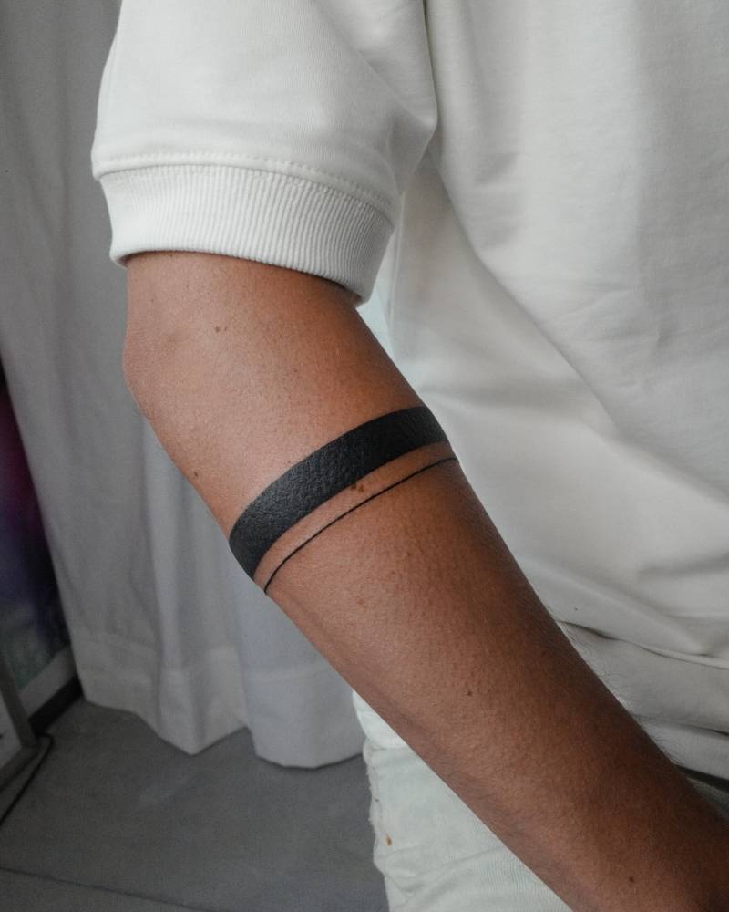 Armband tattoo in blackwork style placed on the forearm.
