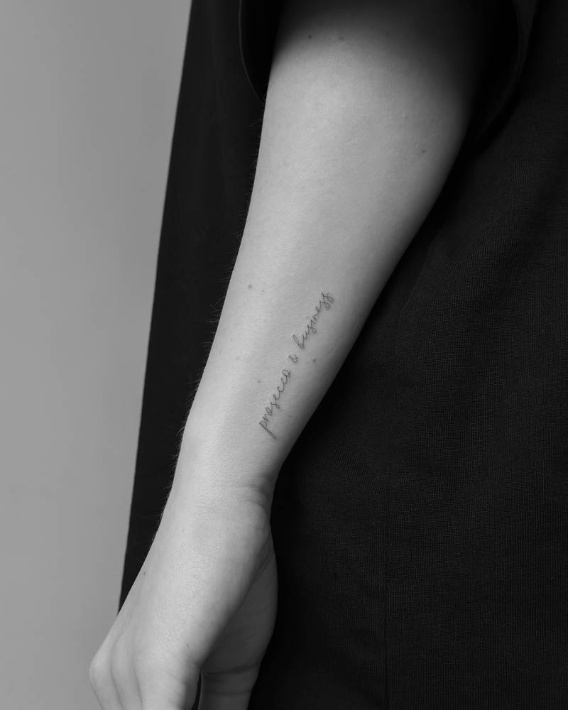 "Prosecco and business" lettering tattoo located on the wrist.