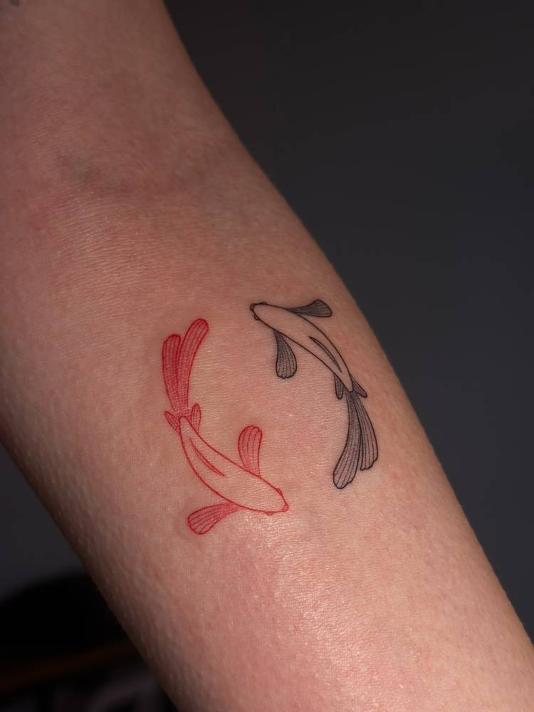 Two opposite fish tattoo located on the inner forearm.