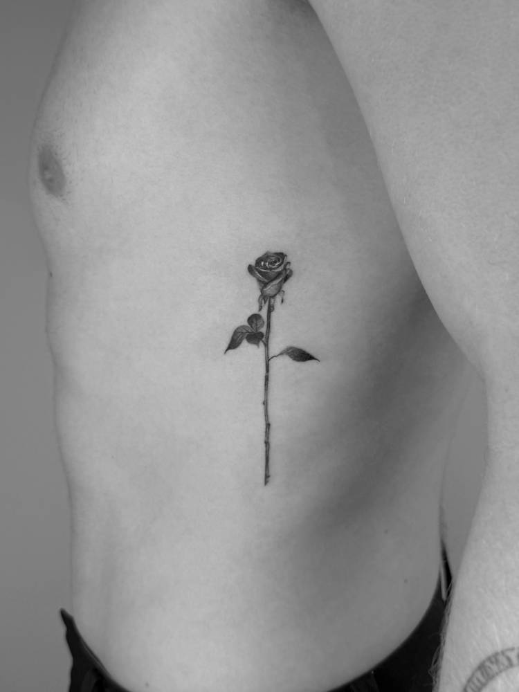 Black and grey rose tattoo located on the rib.