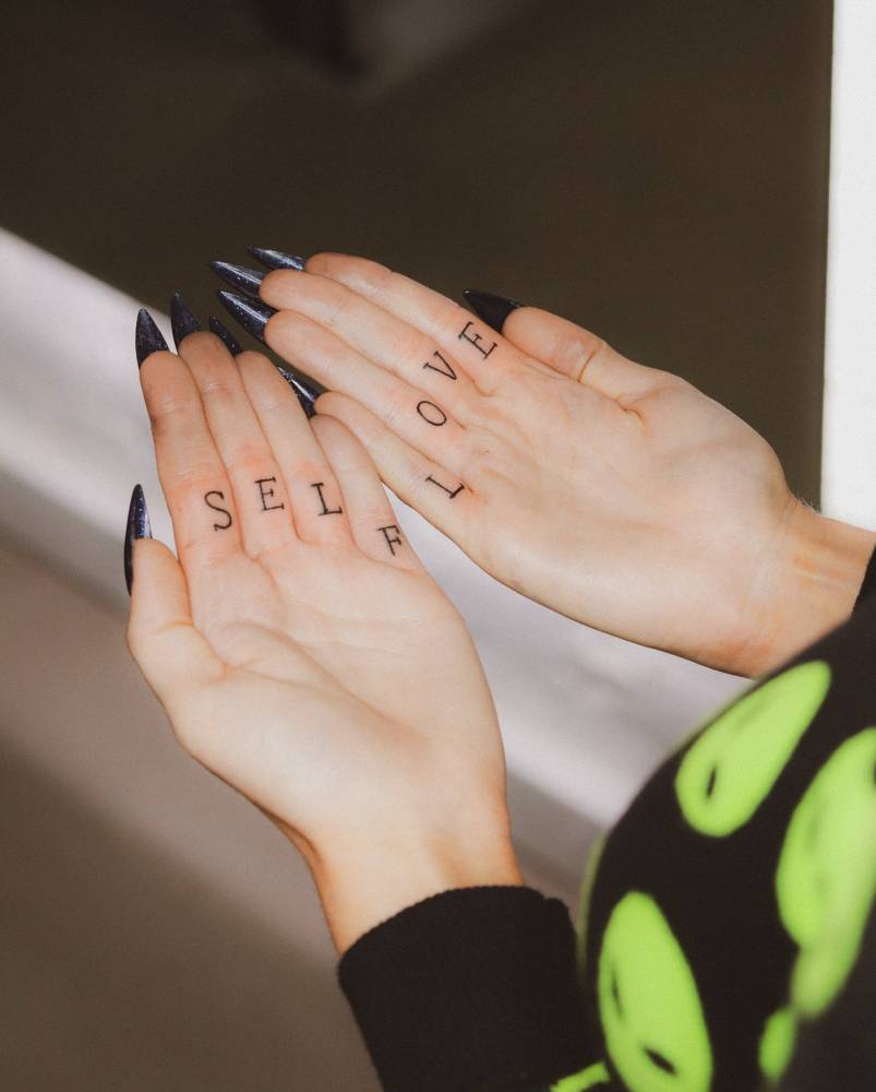 "Self love" individual matching lettering tattoo located on the fingers.