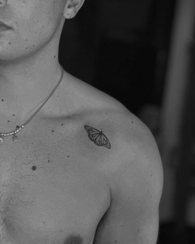 Monarch butterfly tattooed on the shoulder, micro-realistic style.