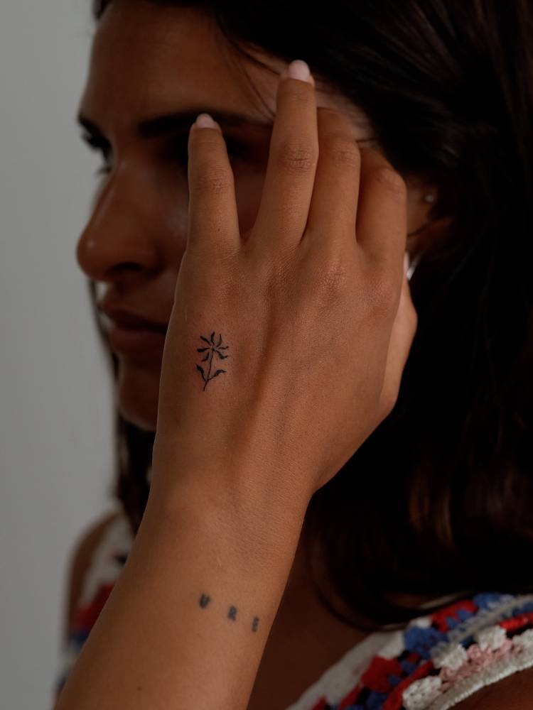 Minimalistic tiny flower tattooed on the hand.