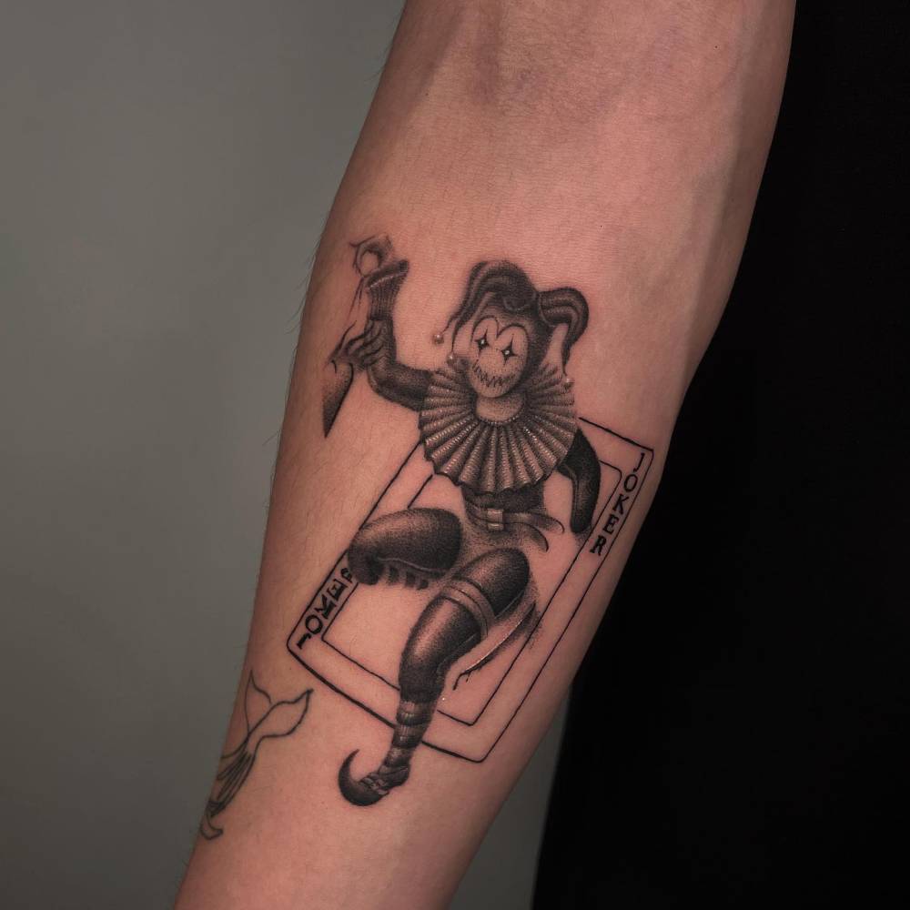 Joker tattoo in blackwork style located on the inner forearm.