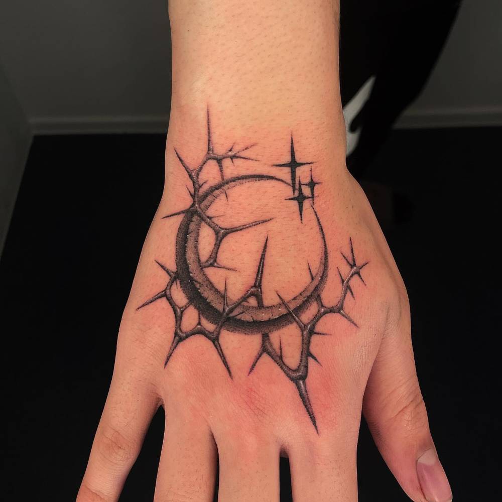 Dotwork style crescent moon and thorns tattoo located on the hand.