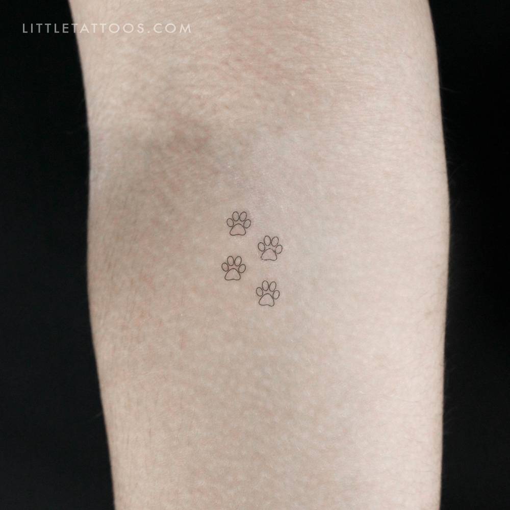 Little paw print outlines temporary tattoo located on the inner forearm.