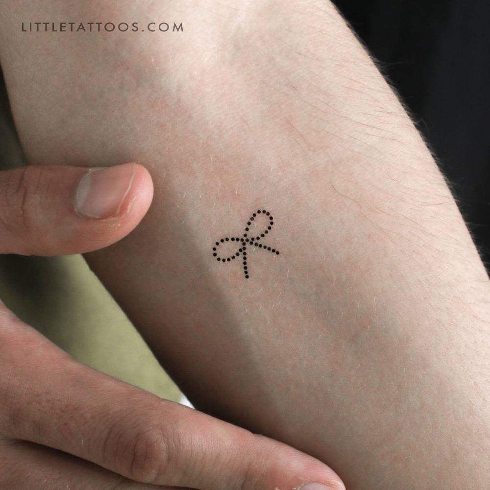 Dot bow temporary tattoo in minimalistic style located on the inner forearm.