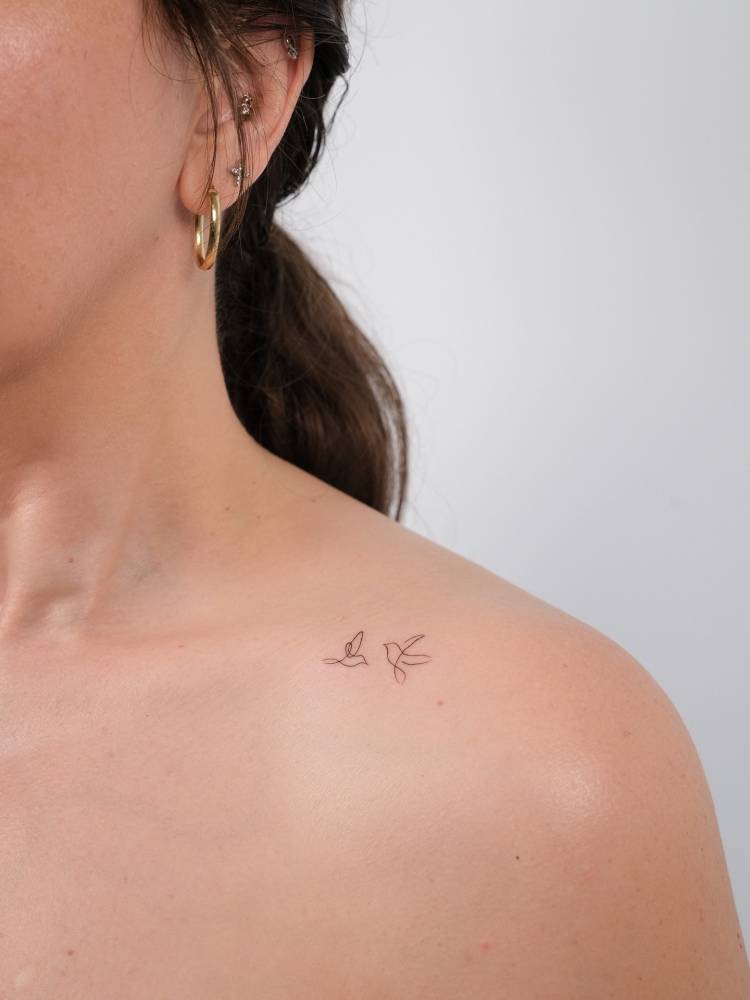 Continuous line flying birds tattooed on the collarbone, minimalistic style.