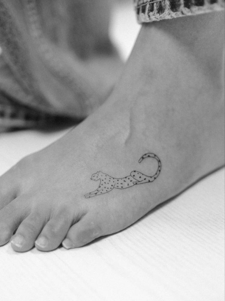 Cheetah tattoo in fine line style placed on the foot.