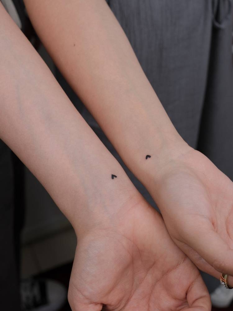 Tiny matching hearts tattoo in minimalistic style for best friends.