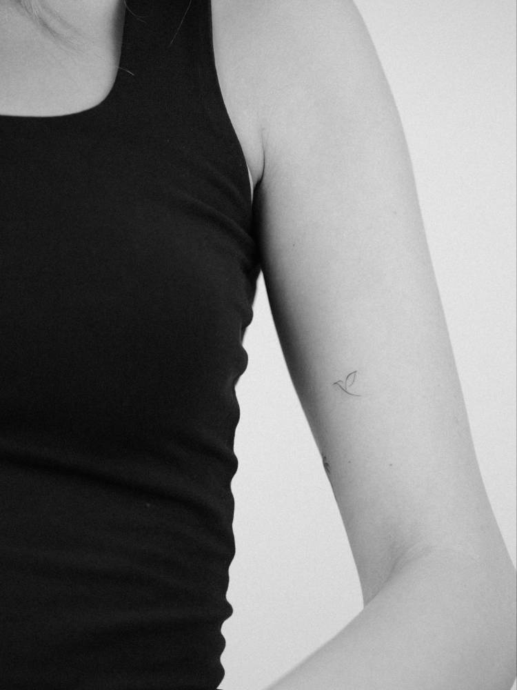 Minimalistic tiny Tatteco logo tattooed on the upper arm.