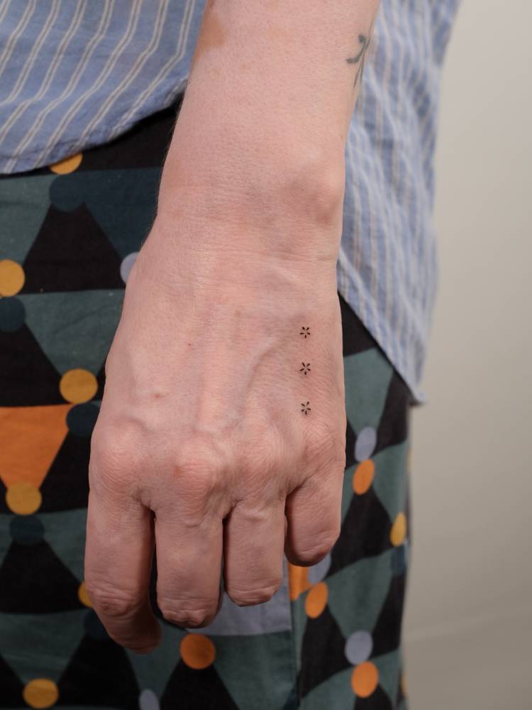 Minimalistic three little flowers tattooed on the hand.