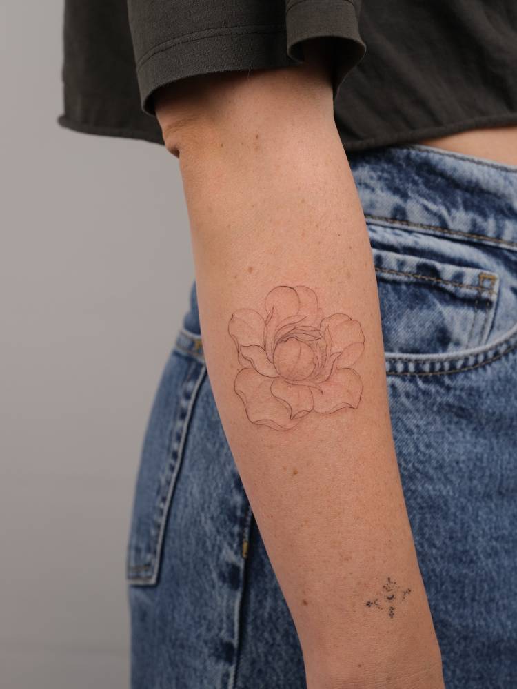 Peony flower tattoo located on the forearm, done in fine line style.