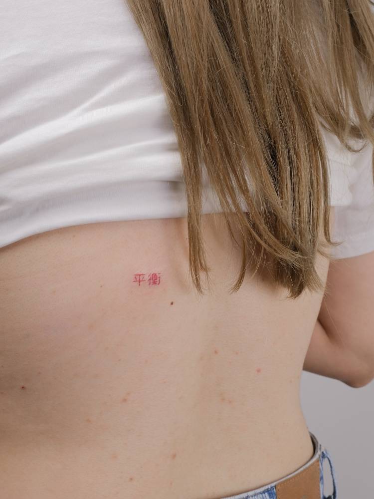 Chinese lettering tattoo in red ink located on the back.