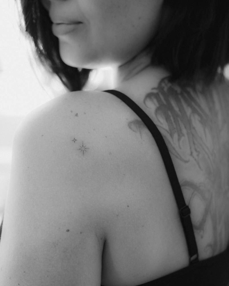 Sparkling stars tattoo in fine line style placed on the shoulder blade.