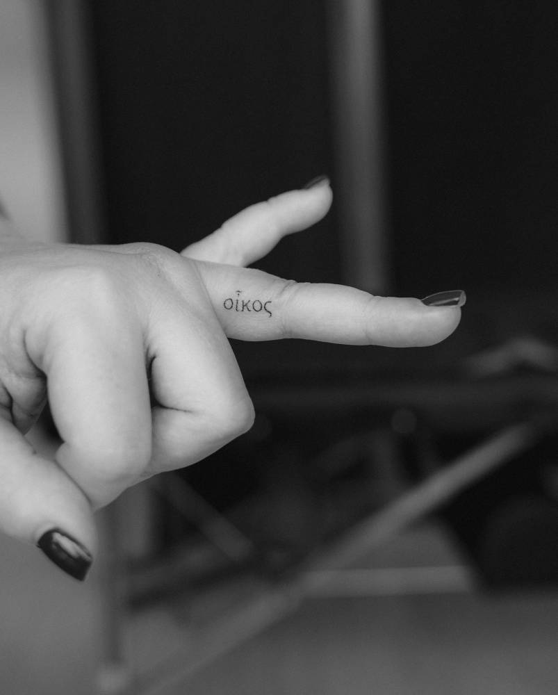 Greek lettering tattoo located on the finger.
