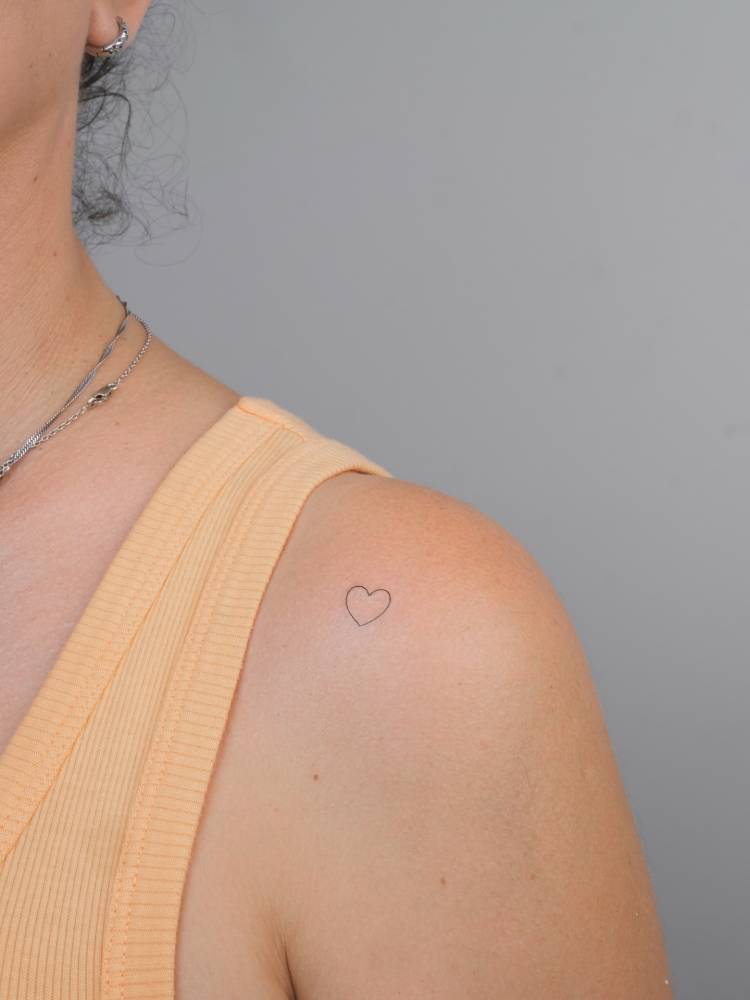 Minimalistic style heart tattoo located on the shoulder.