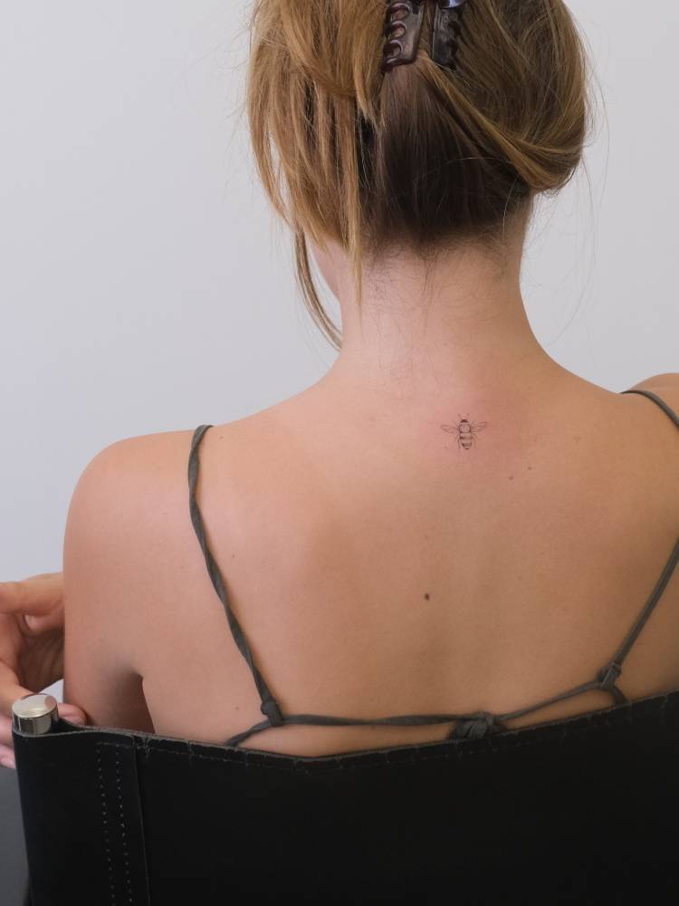 Single needle bee tattoo located on the upper back.