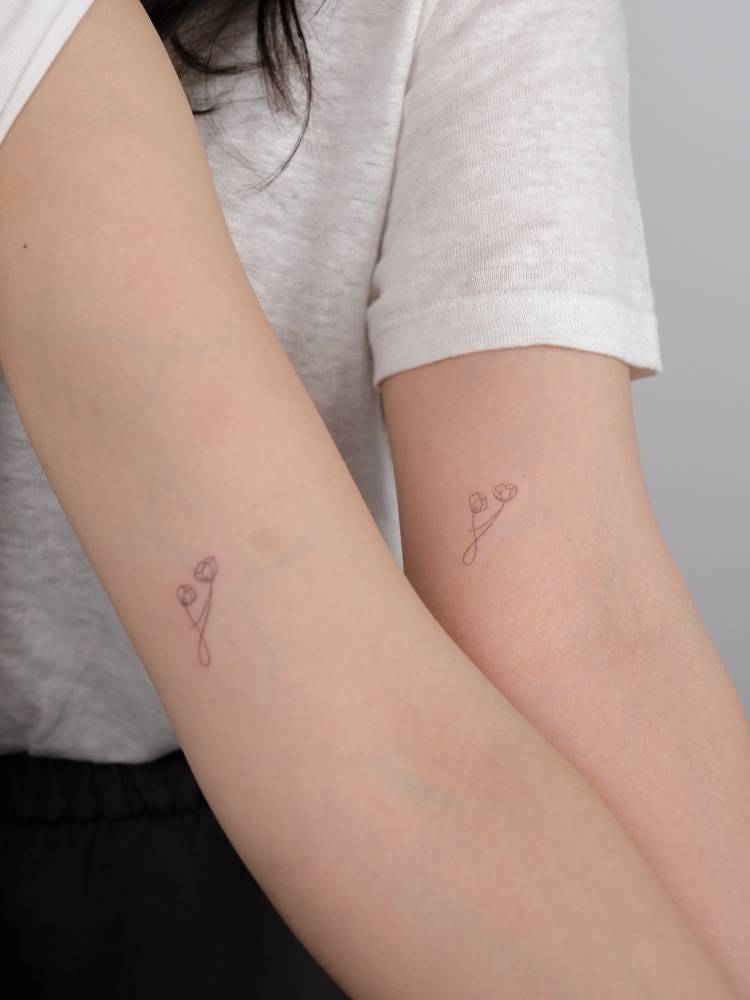 Matching fine line style mother and daughter symbol tattoo.
