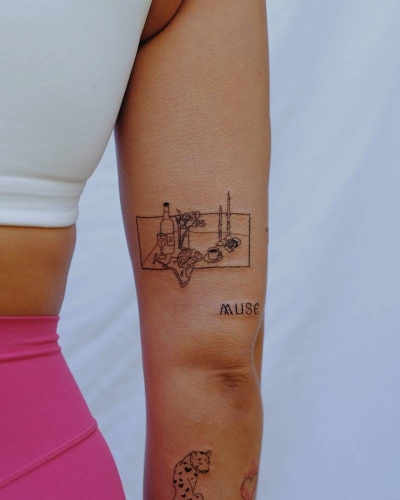 Fine line style still life tattoo located on the tricep.