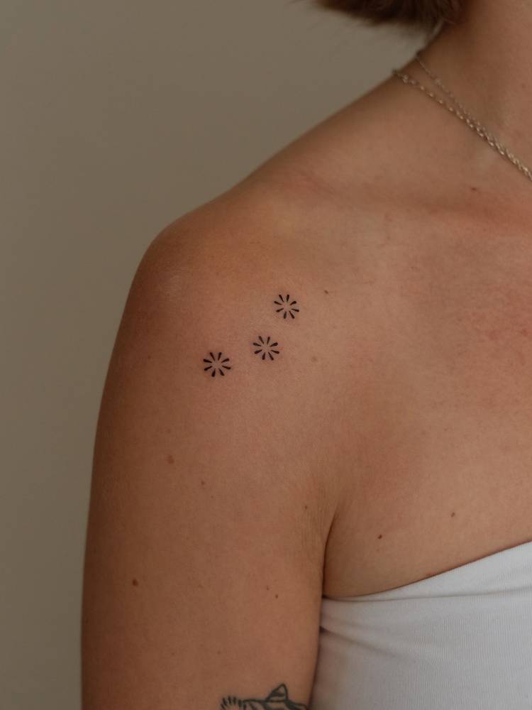 Minimalistic style flowers tattooed on the shoulder.