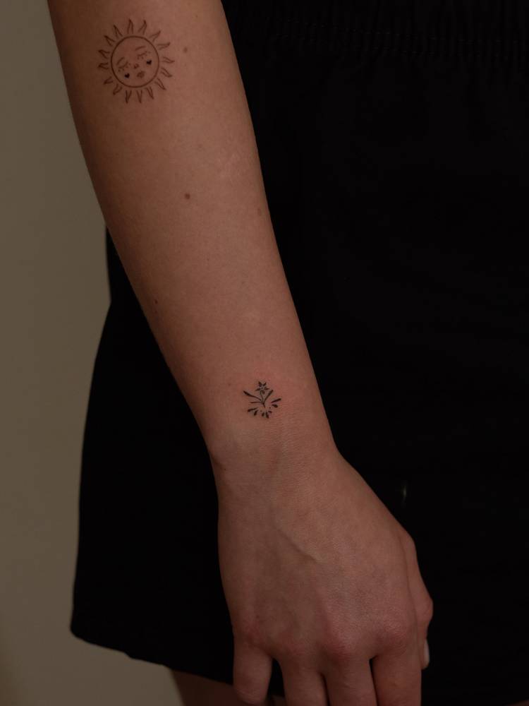 Tiny ornamental flower tattoo placed on the wrist.
