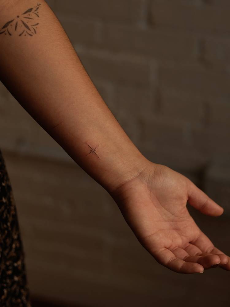 Little north star tattoo in minimalistic style located on the wrist.