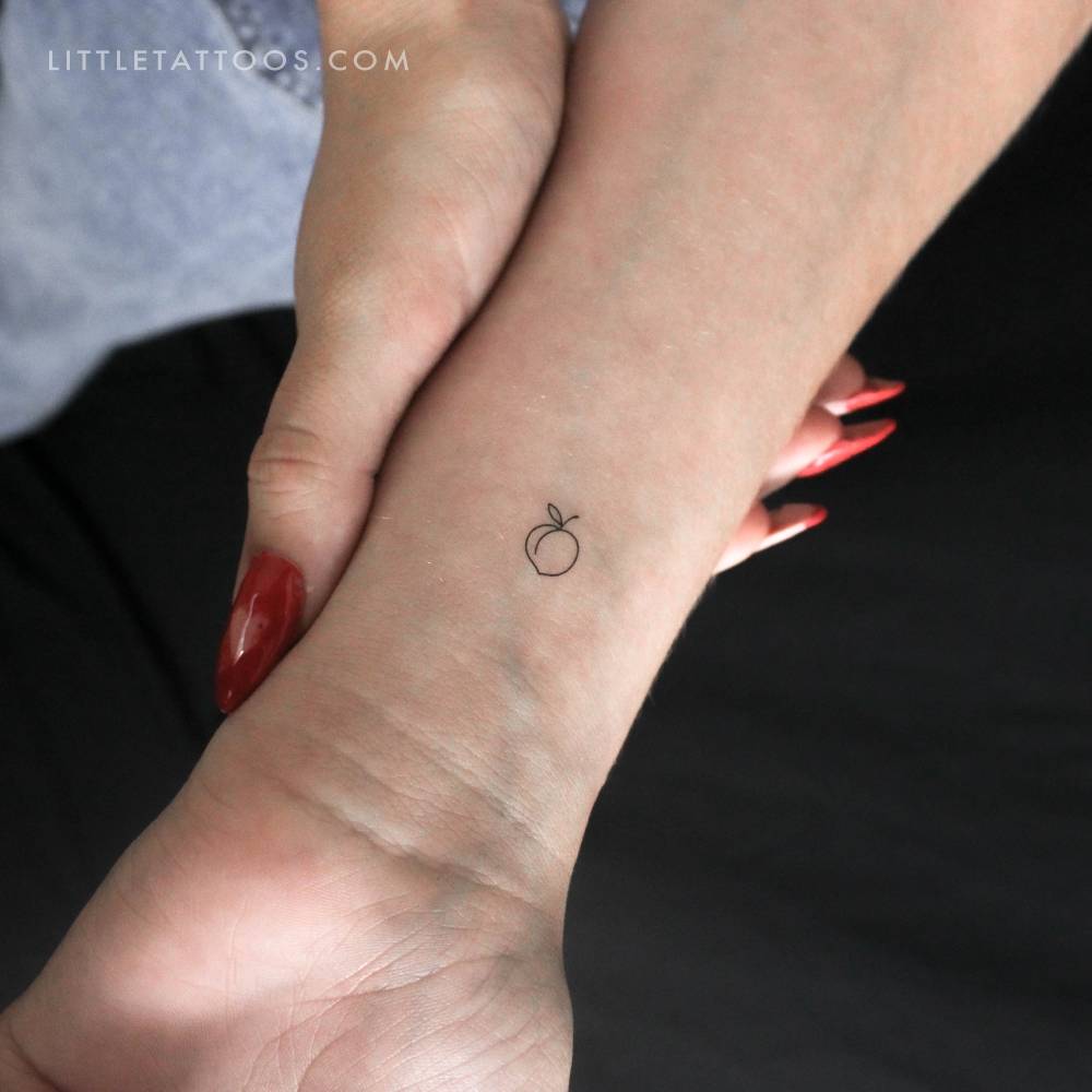 Tiny minimalistic peach temporary tattoo located on the wrist.