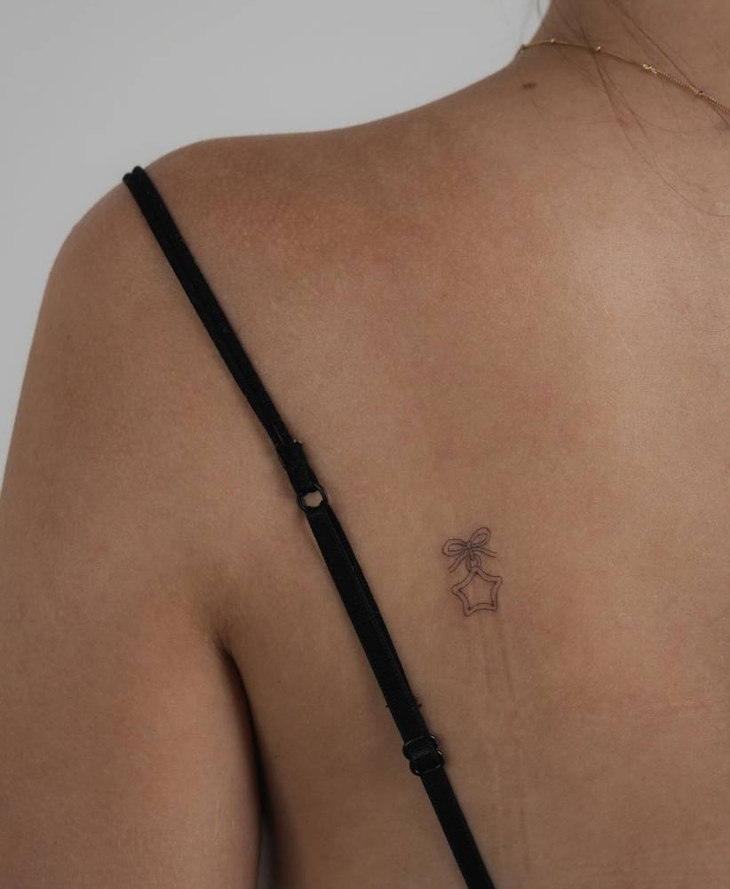 Star pendant tattoo in fine line style done on the shoulder blade.