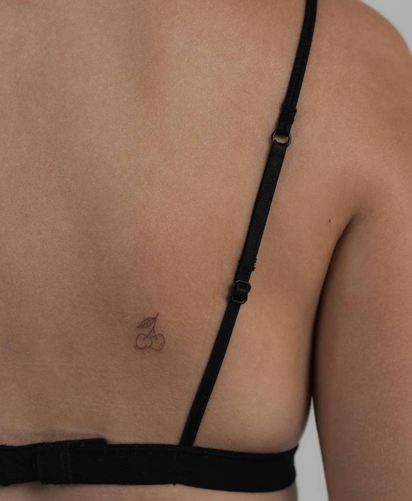 Tiny cherries tattooed on the back, done in fine line style.