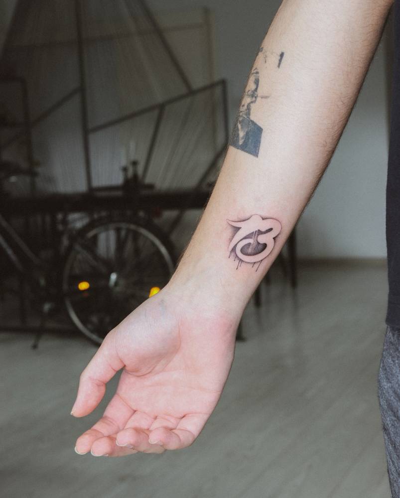 Lettering tattoo of the number "13" located on the wrist.