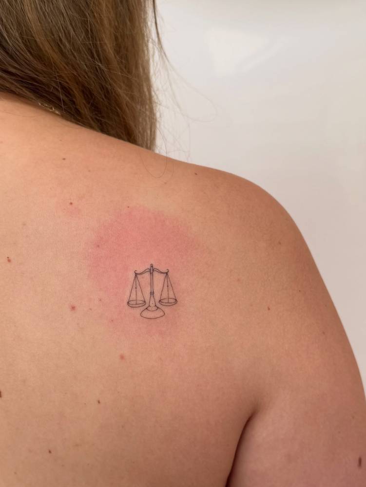 Scale tattoo in fine line style placed on the shoulder blade.