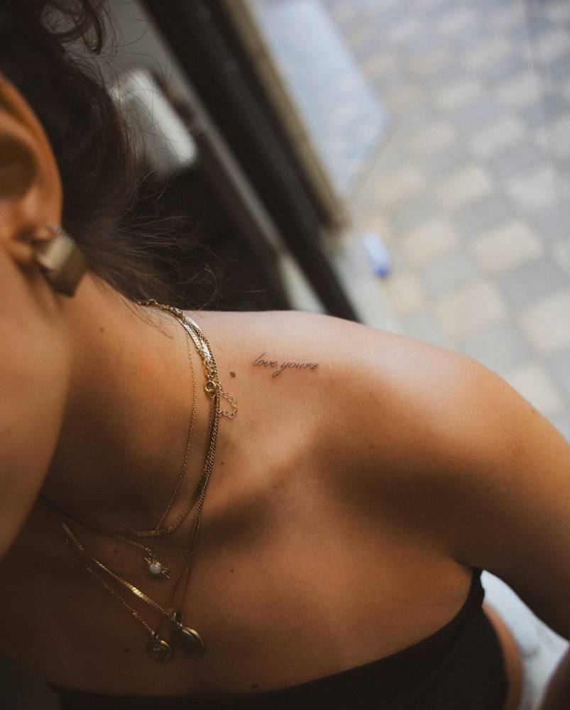 "Love yourz" lettering tattoo located on the top of shoulder.