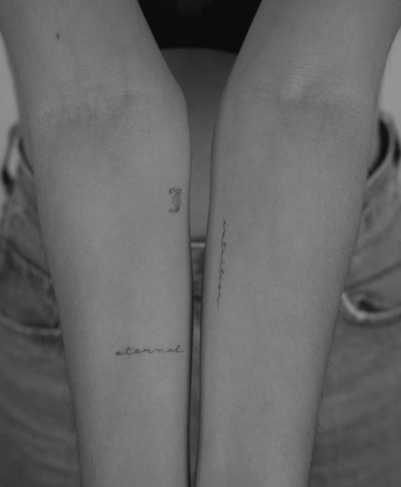Words letter "J", "eternal" and "intuition" tattooed on the inner forearms.