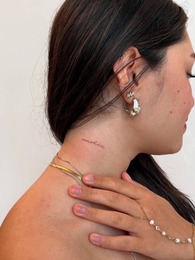 Handwritten font word "sunshine" tattooed on the neck.