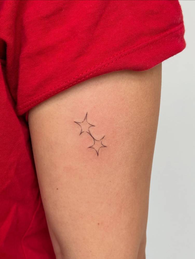 Minimalistic style star couple tattoo done on the thigh.