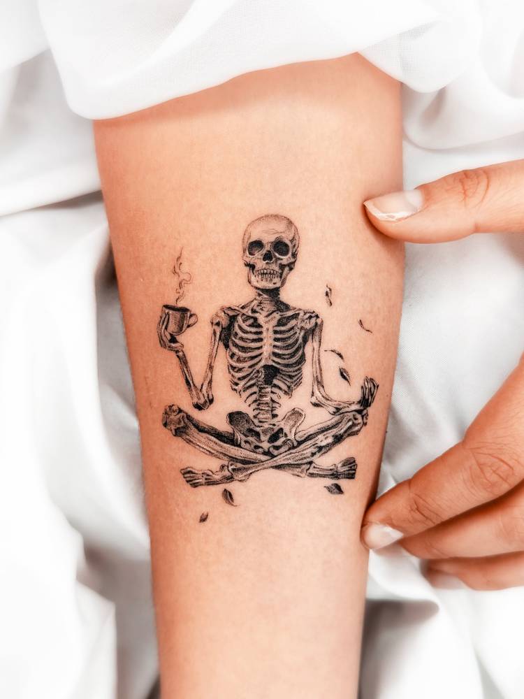Meditating skeleton tattoo located on the inner forearm, micro-realistic style.