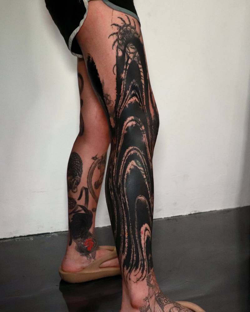 Abstract style cover-up leg tattoo.