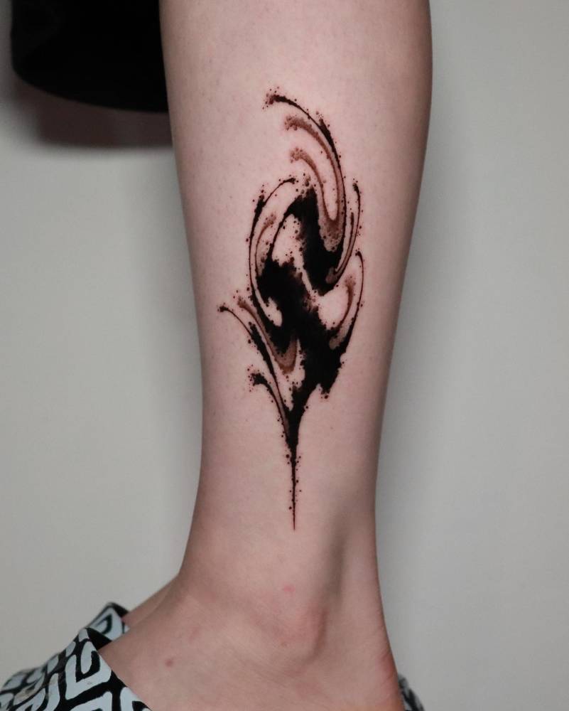 Abstract letter "S" tattoo in blackwork style placed on the shin.