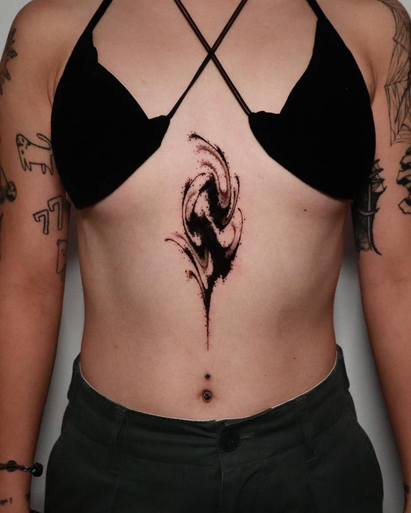 Abstract letter "S" tattoo in blackwork style done on the stomach.