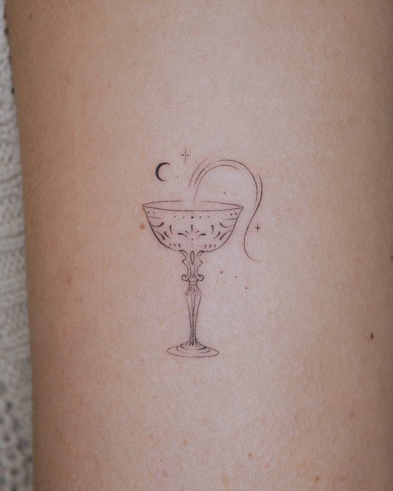 Chalice tattoo in fine line style placed on the upper arm.