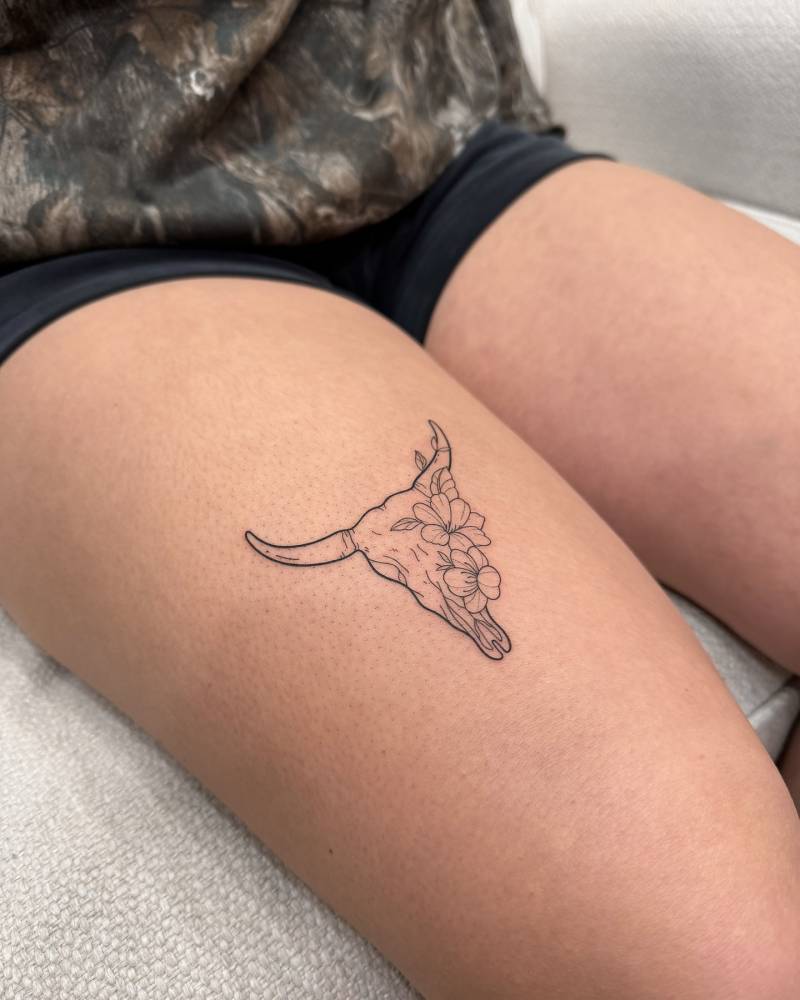 Bull skull tattoo located on the thigh, done in fine line style.