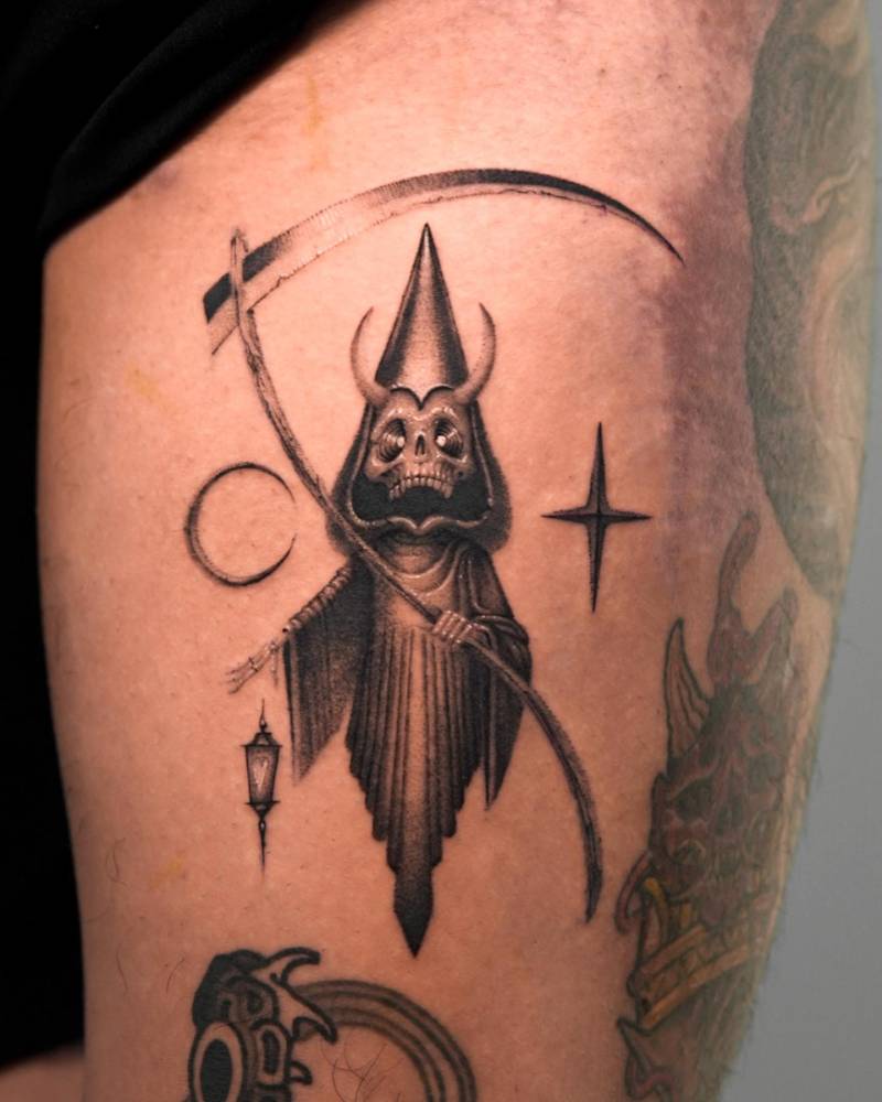 Cartoony style Grim Reaper tattoo located on the thigh.
